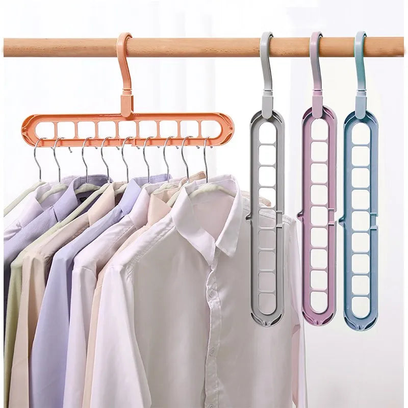 A set of four plastic hanger bars in peach, silver, lavender, and blue, shown hanging from a wooden rod alongside shirts on hangers.