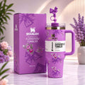 Purple Stanley tumbler with floral design and packaging on a light background